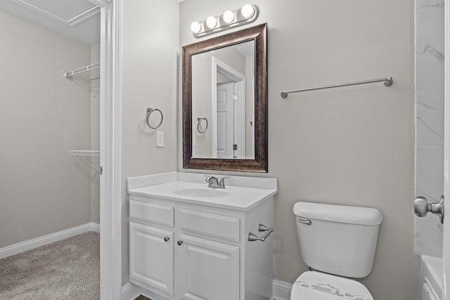 full bath with toilet, a walk in closet, vanity, and baseboards