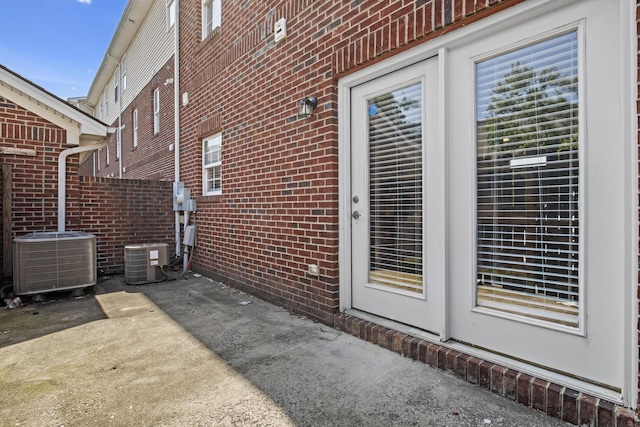 exterior space with central AC unit, a patio, and brick siding