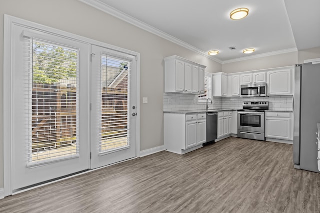 kitchen with crown molding, decorative backsplash, stainless steel appliances, and wood finished floors