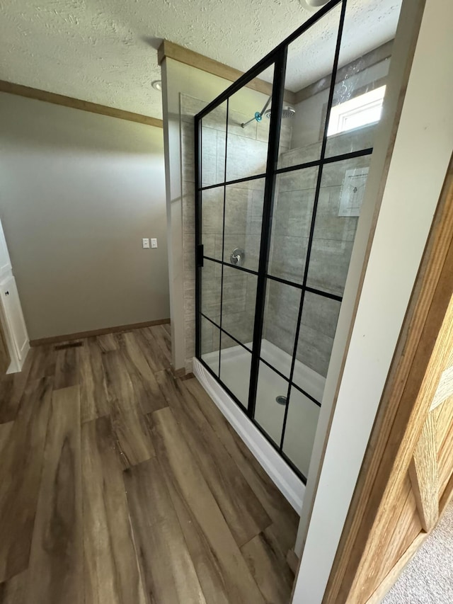 bathroom with hardwood / wood-style floors, a shower with door, and crown molding