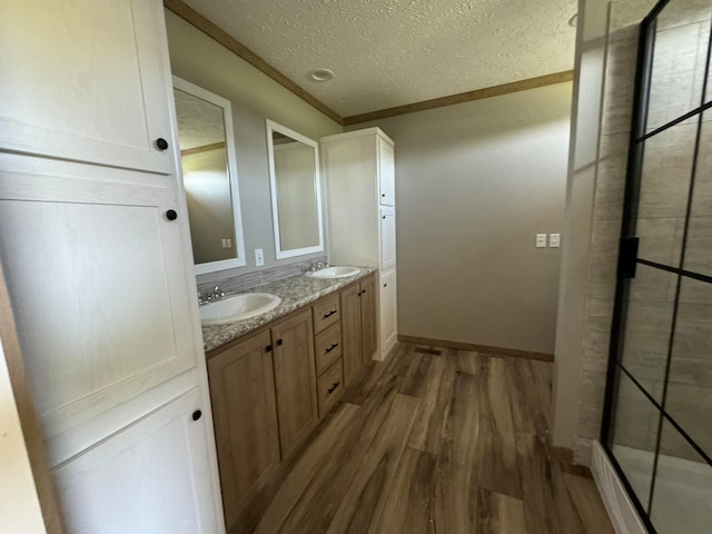 bathroom featuring crown molding, hardwood / wood-style floors, vanity, and a textured ceiling