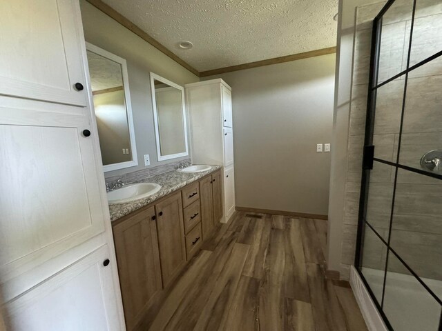 bathroom featuring hardwood / wood-style floors, vanity, crown molding, a textured ceiling, and walk in shower