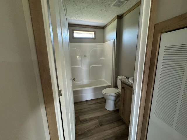 full bathroom featuring hardwood / wood-style floors, vanity, shower / tub combination, toilet, and a textured ceiling