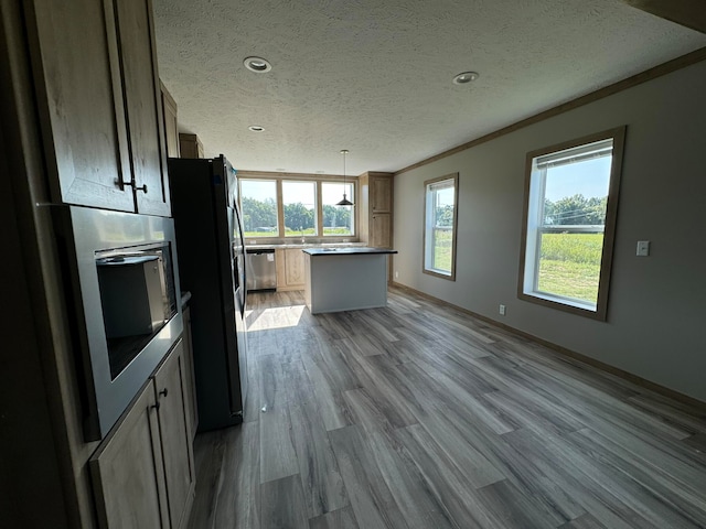 kitchen featuring a center island, stainless steel appliances, light hardwood / wood-style flooring, decorative light fixtures, and ornamental molding