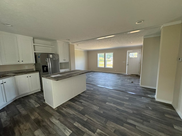 kitchen with white cabinets, dark hardwood / wood-style flooring, stainless steel refrigerator with ice dispenser, a kitchen island, and a textured ceiling