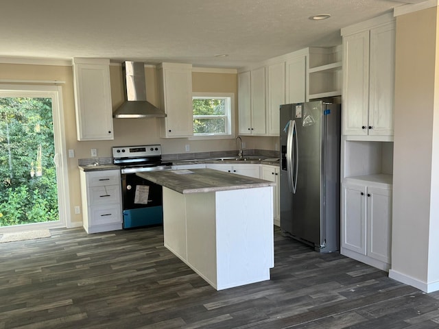 kitchen with a center island, stainless steel appliances, white cabinets, and wall chimney range hood