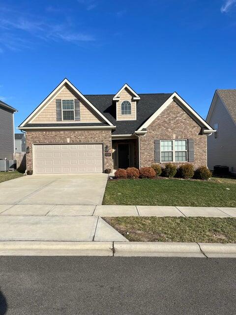 view of front of home with central AC, a front yard, and a garage