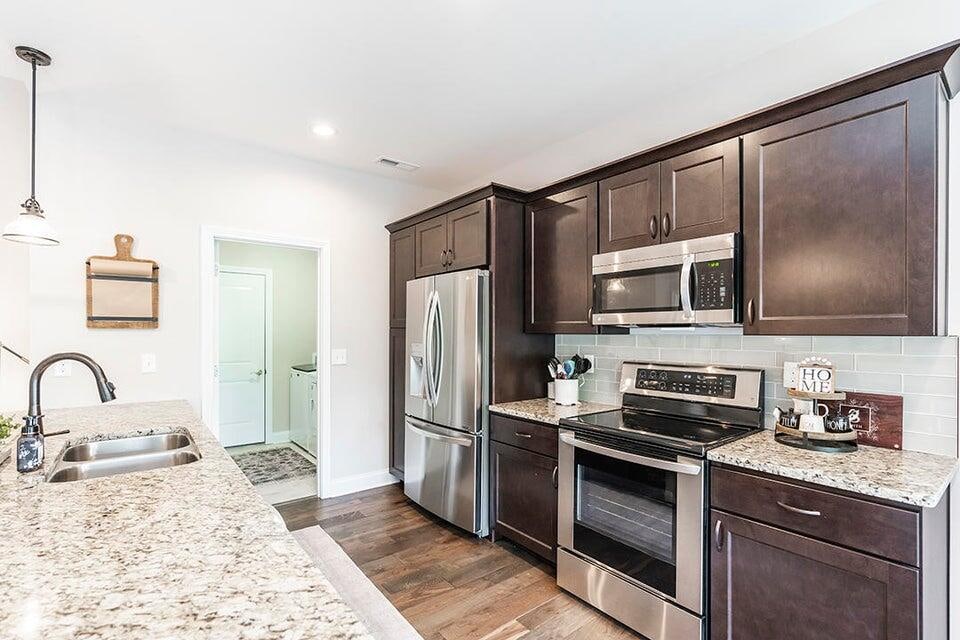 kitchen featuring light stone counters, hanging light fixtures, sink, appliances with stainless steel finishes, and dark hardwood / wood-style flooring