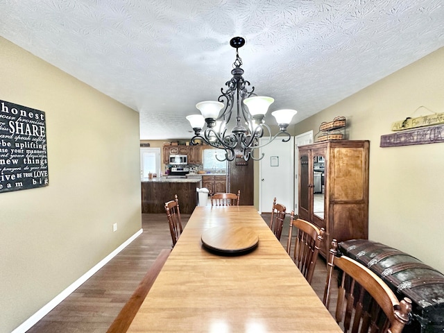 dining space with a textured ceiling, light hardwood / wood-style flooring, and an inviting chandelier