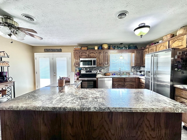 kitchen with stainless steel appliances, sink, a large island, and tasteful backsplash