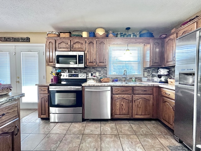 kitchen with a healthy amount of sunlight, stainless steel appliances, sink, and decorative backsplash