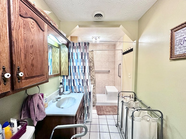 bathroom featuring tile patterned flooring, walk in shower, a textured ceiling, and vanity