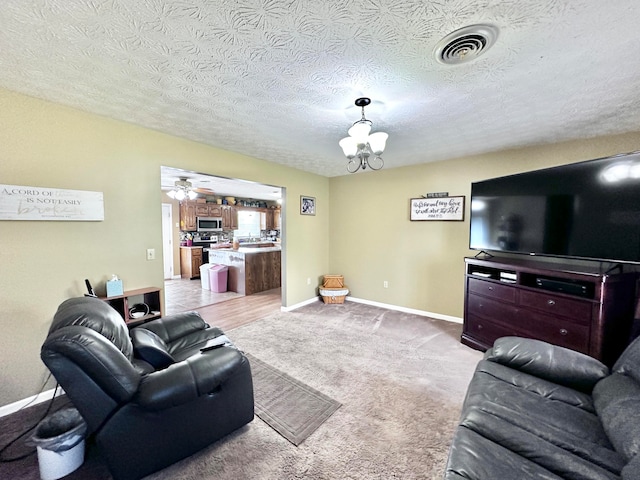 living room featuring a textured ceiling, ceiling fan with notable chandelier, and light carpet