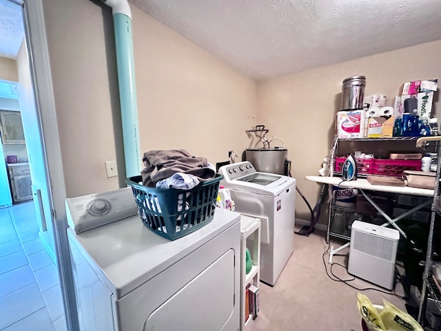 laundry room featuring washing machine and clothes dryer, light colored carpet, a textured ceiling, and water heater