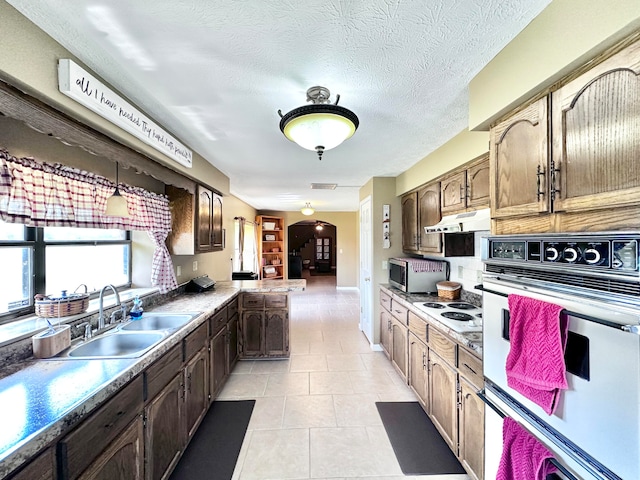 kitchen with white appliances, a textured ceiling, light tile patterned floors, sink, and hanging light fixtures