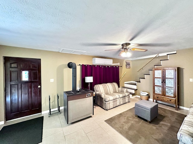 tiled living room with a wood stove, a wall mounted AC, ceiling fan, and a textured ceiling