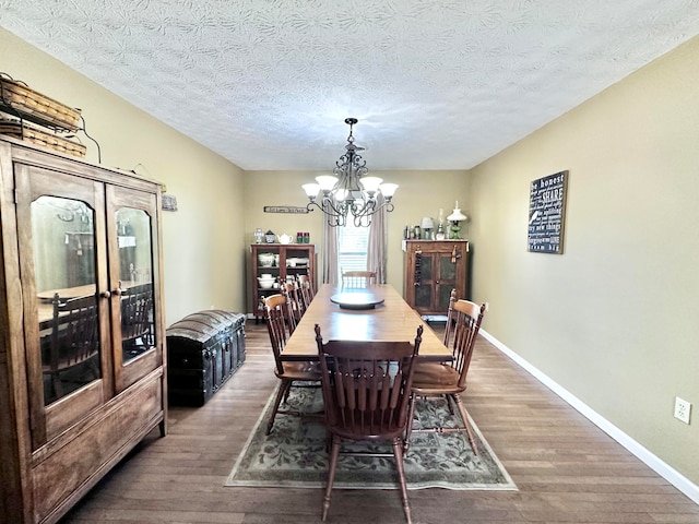 dining room featuring dark hardwood / wood-style floors, an inviting chandelier, and a textured ceiling