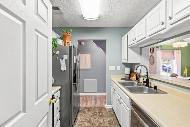 kitchen featuring sink, dark tile patterned floors, a textured ceiling, stainless steel appliances, and white cabinets