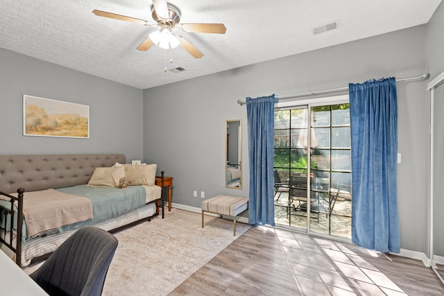 bedroom with ceiling fan, light hardwood / wood-style floors, and a textured ceiling