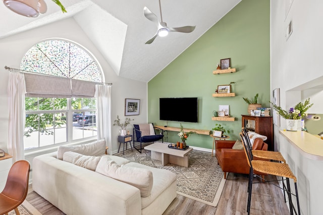 living room featuring light hardwood / wood-style flooring, ceiling fan, and high vaulted ceiling