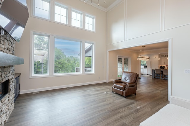 sitting room featuring a fireplace, a towering ceiling, ornamental molding, wood finished floors, and baseboards