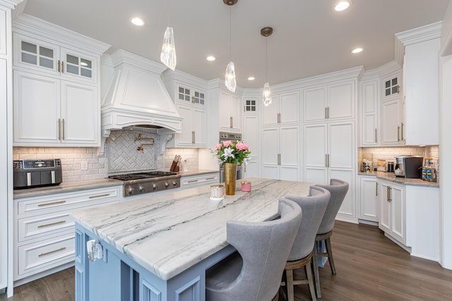 kitchen with premium range hood, a kitchen island, glass insert cabinets, and white cabinets