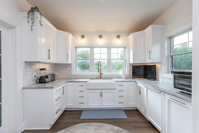 kitchen with a sink, white cabinetry, and light stone countertops