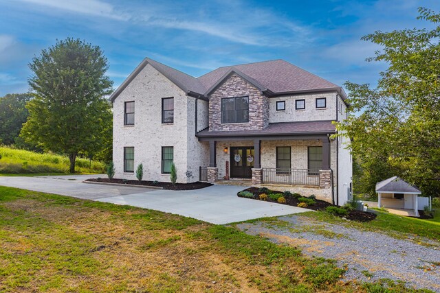 view of front facade with a garage, a front yard, a porch, and an outbuilding