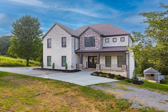 view of front of home with a shingled roof, a front yard, a porch, central AC, and brick siding