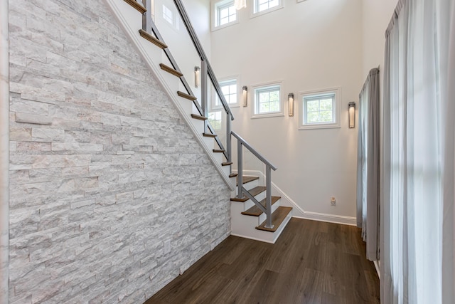 foyer entrance featuring dark wood-style floors, a wealth of natural light, stairway, and a towering ceiling