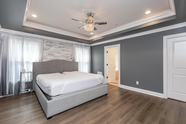 bedroom with a tray ceiling, dark wood-type flooring, and baseboards