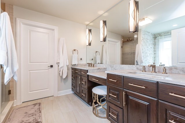 bathroom with baseboards, double vanity, a sink, and a shower stall