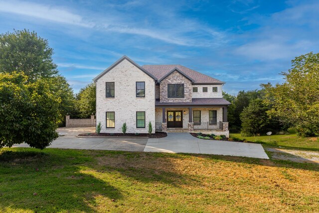 view of front of house featuring a porch, stone siding, and a front lawn