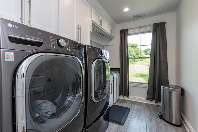 laundry room with wood finished floors, visible vents, baseboards, cabinet space, and washer and clothes dryer