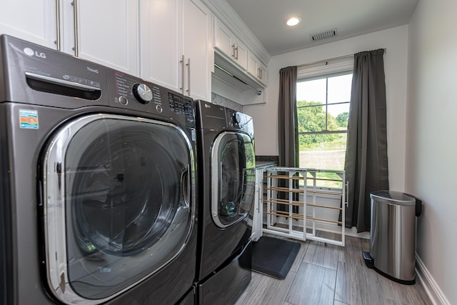 washroom featuring cabinet space, visible vents, baseboards, and separate washer and dryer