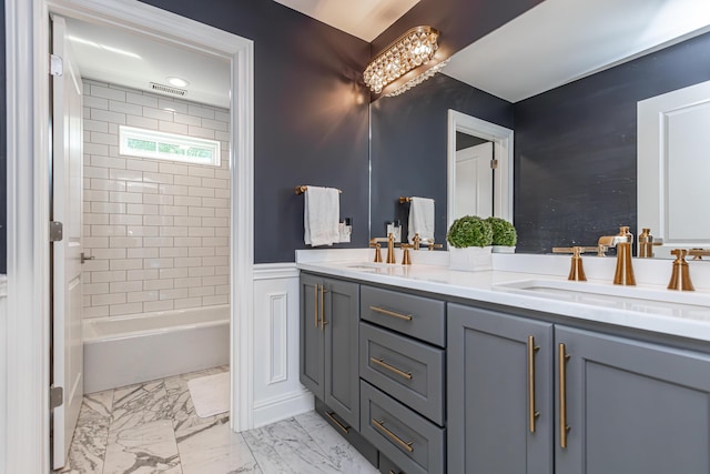 full bath featuring shower / washtub combination, marble finish floor, a wainscoted wall, double vanity, and a sink