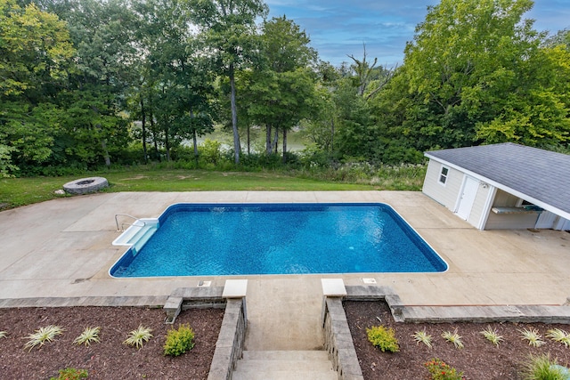 outdoor pool featuring an outbuilding, an exterior structure, a patio, and a lawn