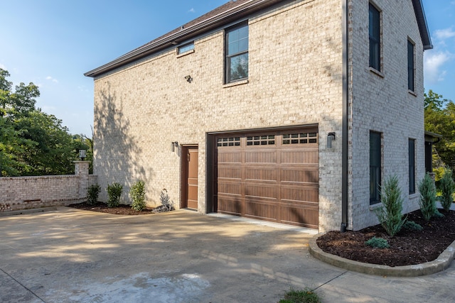 view of side of property featuring a garage, driveway, and brick siding