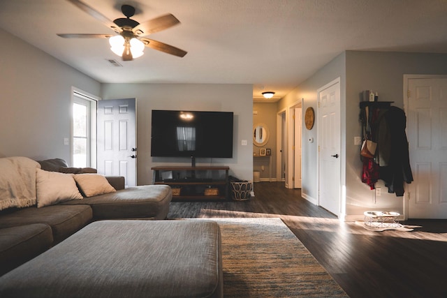 living room featuring ceiling fan and dark wood-type flooring