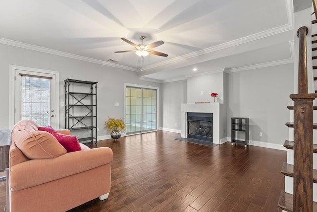 living area featuring wood finished floors, baseboards, visible vents, a fireplace, and crown molding