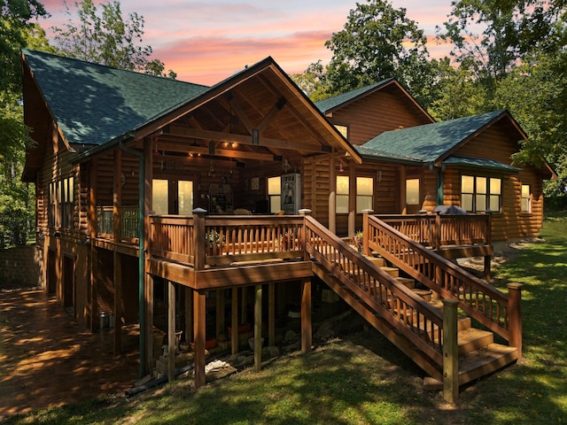 back house at dusk with a wooden deck and a yard