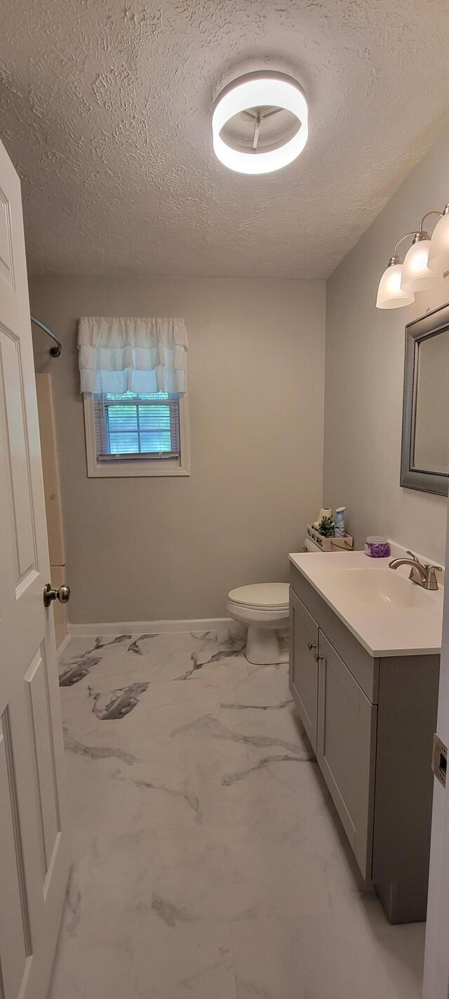 bathroom featuring walk in shower, vanity, a textured ceiling, and toilet