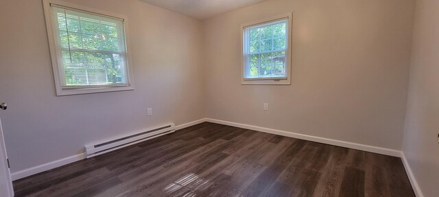 spare room featuring dark wood-type flooring and a baseboard radiator