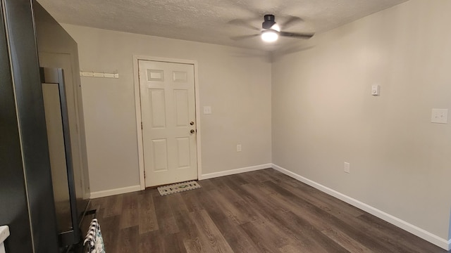 empty room featuring ceiling fan, a textured ceiling, baseboards, and dark wood-type flooring