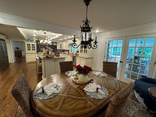 dining area featuring a raised ceiling, a chandelier, french doors, hardwood / wood-style flooring, and crown molding