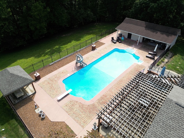 view of swimming pool with a diving board, a yard, a patio, and a water slide