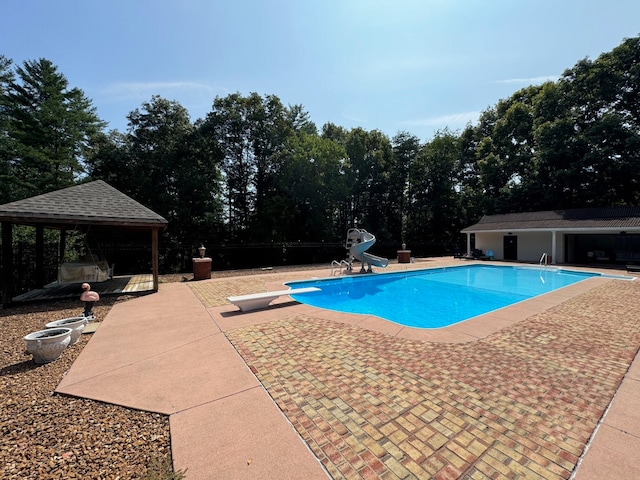 view of swimming pool with a gazebo, a diving board, a patio area, and a water slide