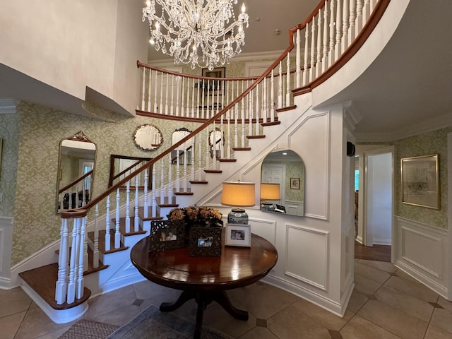 staircase featuring a high ceiling, crown molding, a chandelier, and tile patterned floors