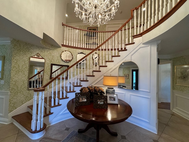 stairs featuring tile patterned flooring, crown molding, a chandelier, and a towering ceiling