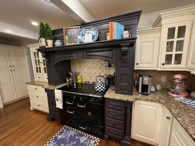 kitchen featuring stone counters, range with electric stovetop, dark wood-type flooring, and tasteful backsplash